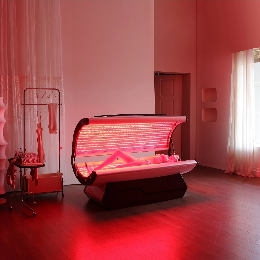 Client lying inside the full-body LED capsule during a red light session